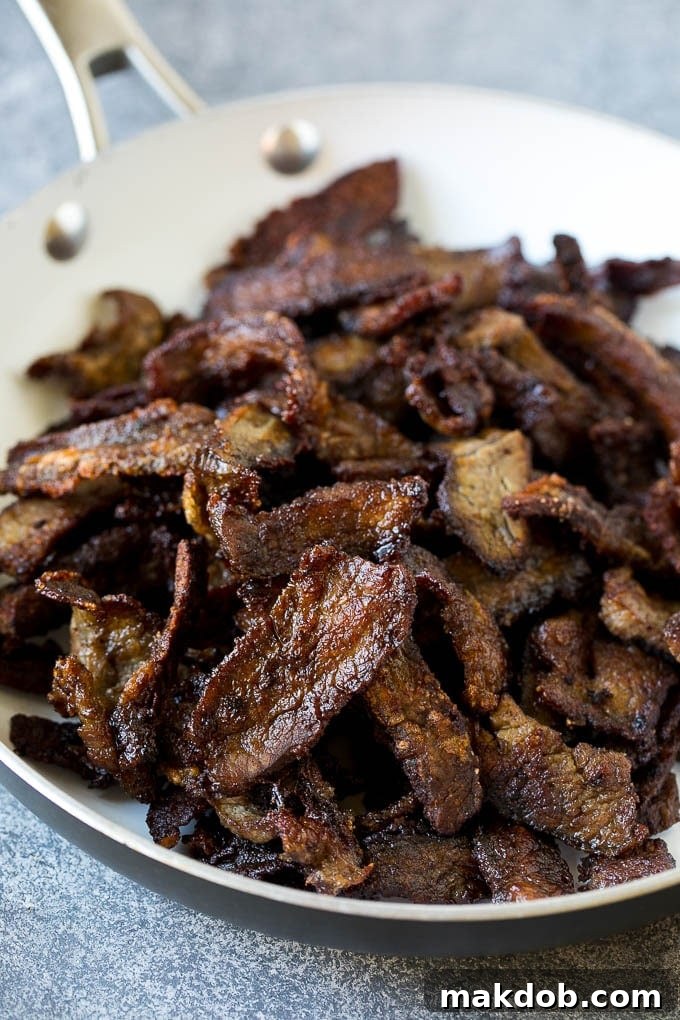 Mongolian Beef Recipe | Asian Beef Recipe | Chinese Beef | Beef Stir Fry #Chinese #Mongolian #Asian #mongolianbeef #beef #dinneratthezoo #dinner Seared crispy flank steak pieces, glistening with sauce, in a pan.