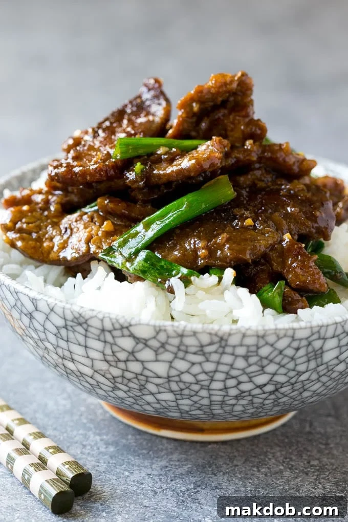 Mongolian Beef Recipe | Asian Beef Recipe | Chinese Beef | Beef Stir Fry #Chinese #Mongolian #Asian #mongolianbeef #beef #dinneratthezoo #dinner A bowl of Mongolian beef served over white rice, garnished with green onions.