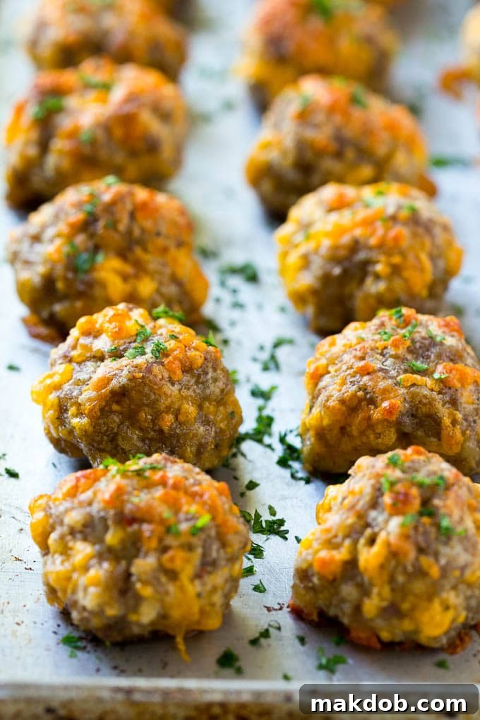 Sausage Cheese Balls Recipe | Sausage Balls Recipe | Bisquick Sausage Balls #sausage #sausageballs #balls #appetizer #cheeseballs #dinneratthezoo Cooked golden-brown sausage cheese balls resting on a baking sheet, ready to be served.