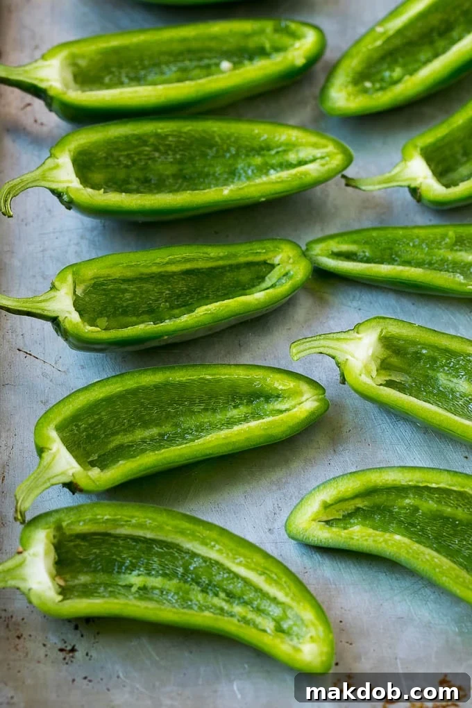 Halved and hollowed out jalapenos on a sheet pan.