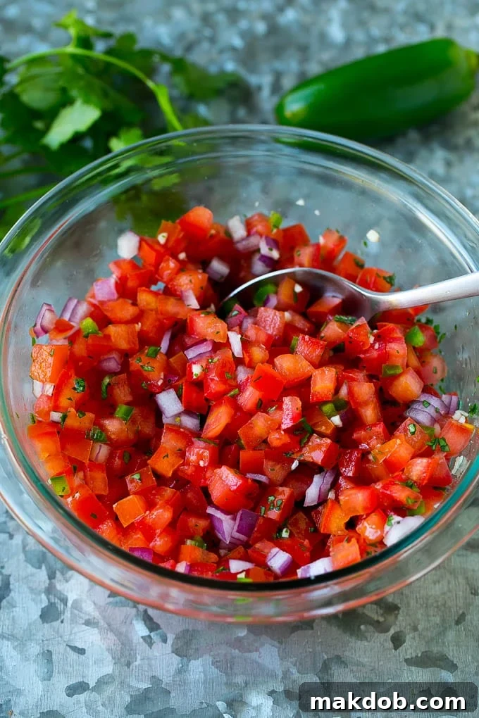 Vibrant Homemade Pico de Gallo 6 Diced tomatoes, cilantro, red onion, and jalapeño beautifully mixed together in a clear glass bowl, showcasing the fresh ingredients of the salsa.