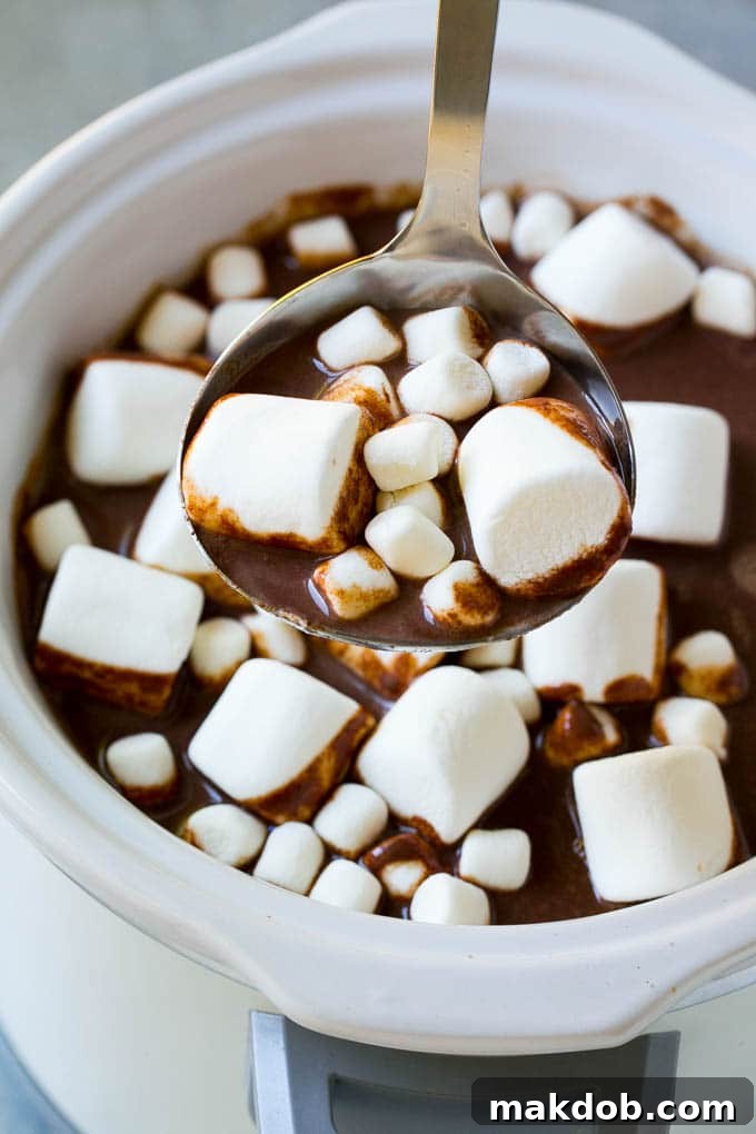 Slow Cooker Hot Chocolate Recipe | Homemade Hot Chocolate | Slow Cooker Hot Cocoa | Crock Pot Hot Chocolate #cocoa #hotchocolate #chocolate #slowcooker #crockpot #holiday #christmas #drink A ladle full of rich, creamy slow cooker hot chocolate topped with fluffy marshmallows, ready to be served.