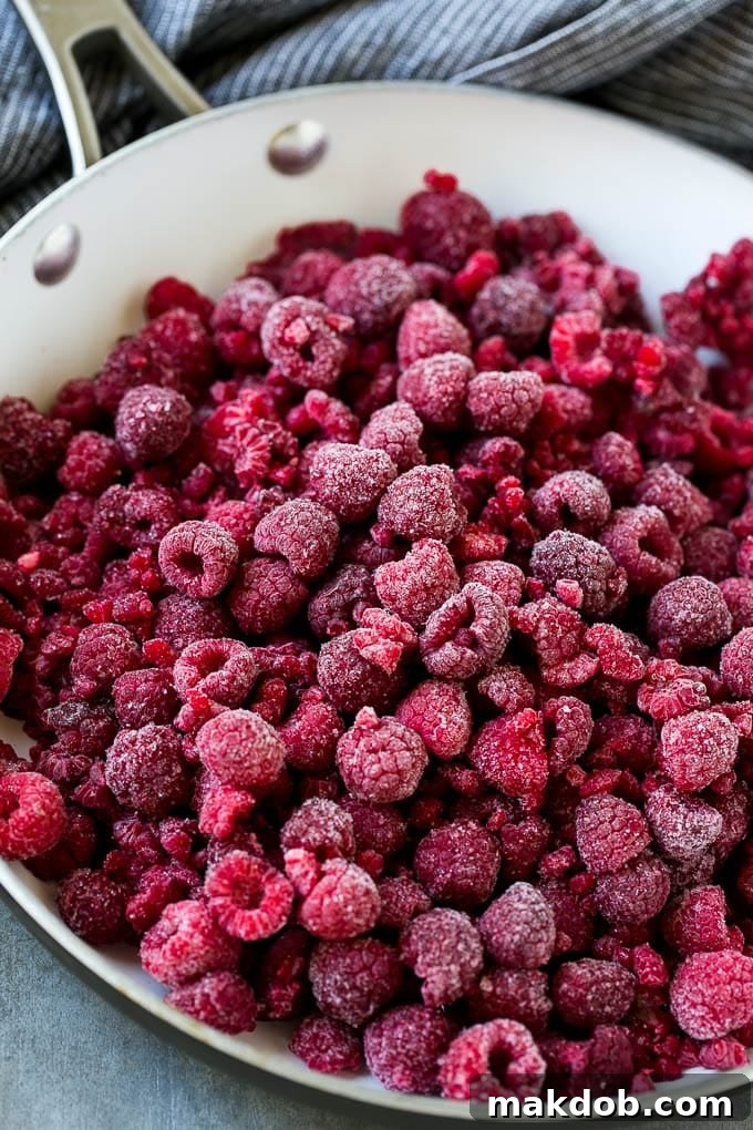 A pan filled with vibrant frozen raspberries, ready to be cooked into a delicious sauce.