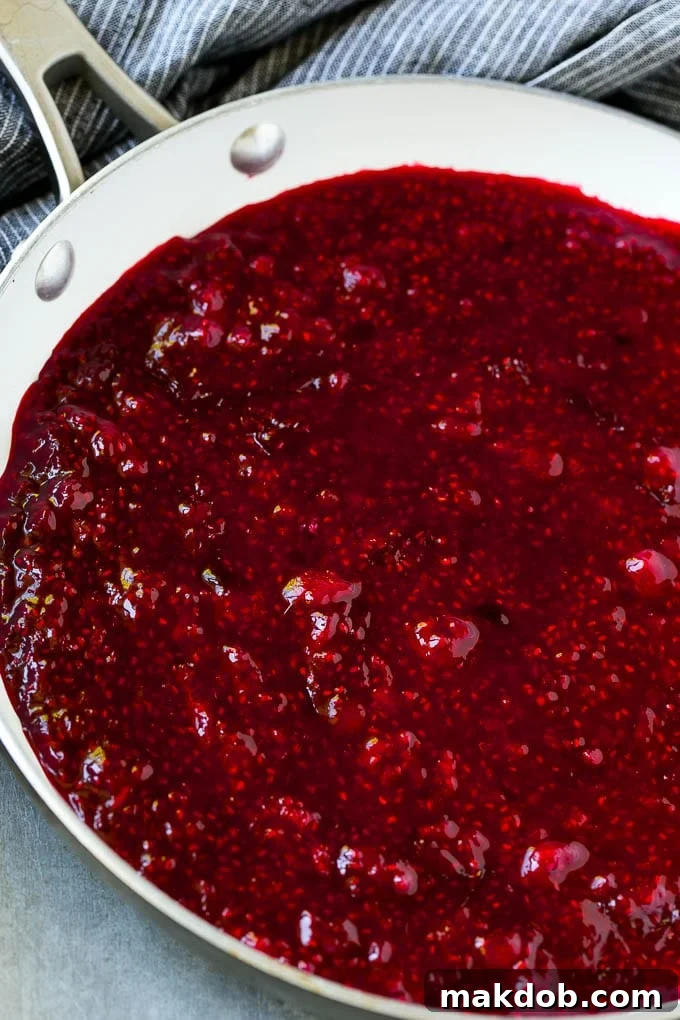 Fresh raspberries simmering in a skillet, turning into a rich, aromatic sauce.