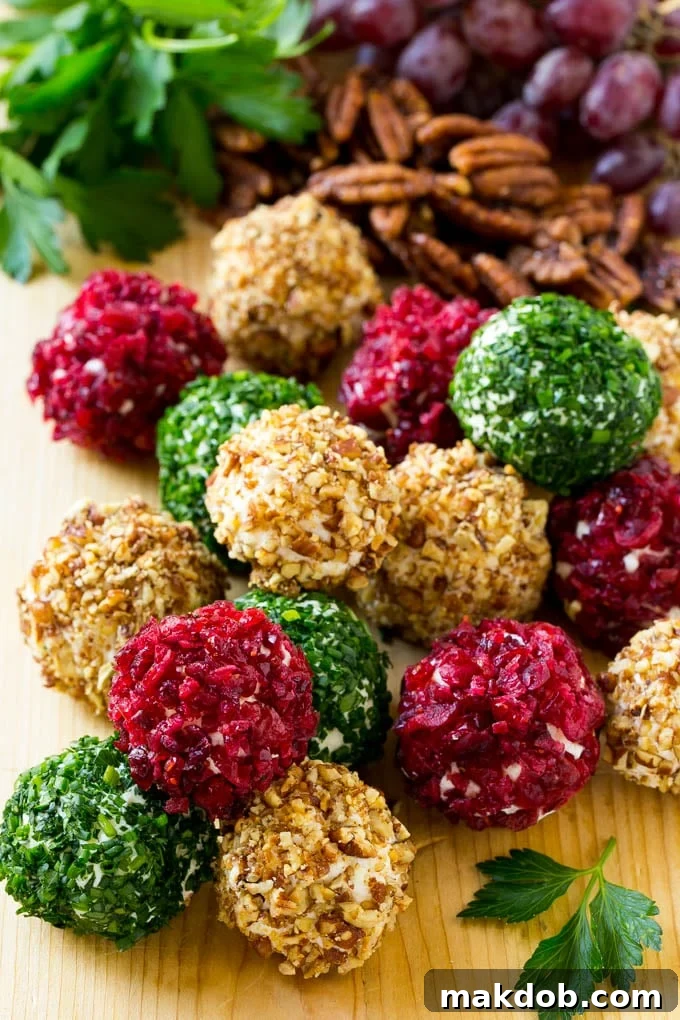 Assorted cheese ball bites rolled in pecans, cranberries, and herbs, served elegantly with fresh fruit and nuts for a sophisticated party display.