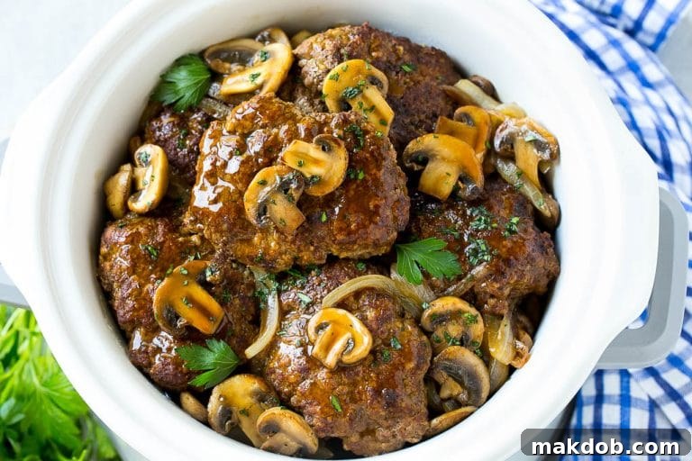 Slow Cooker Salisbury Steak Recipe | Homemade Salisbury Steak | Salisbury Steak from Scratch #steak #beef #salisbury #salisburysteak #slowcooker #crockpot #dinner #dinneratthezoo A crock pot full of slow cooker salisbury steak.