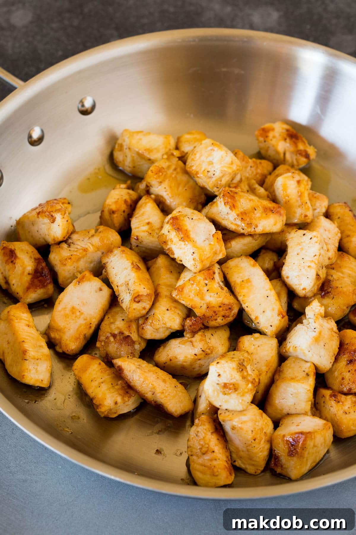 Sauteed chicken pieces with minced garlic in a skillet, ready to be removed for the next step of the pasta recipe.