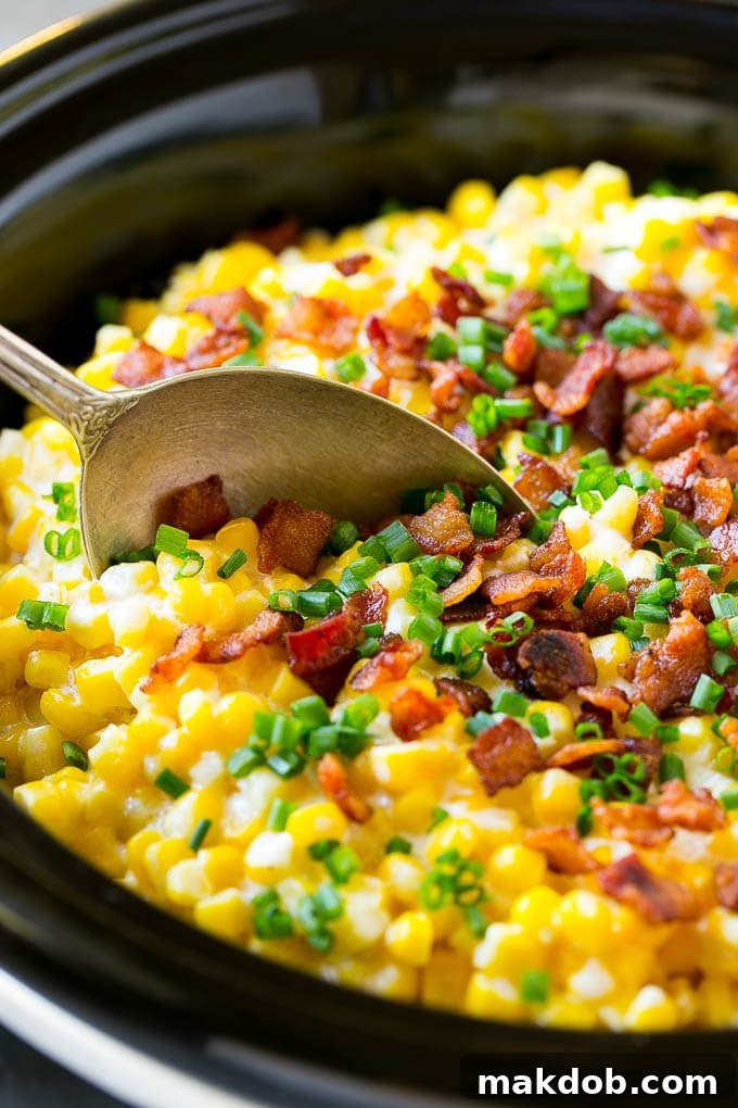 A serving spoon in a crock pot full of creamed corn.