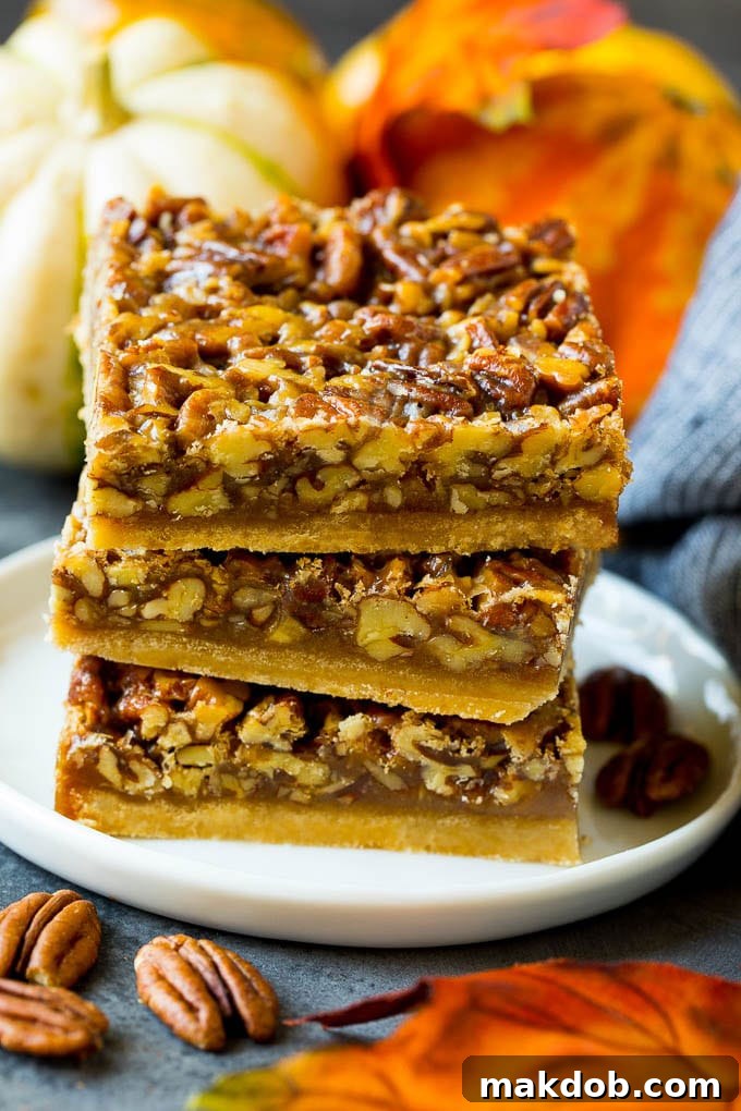 A stack of perfectly cut pecan pie bars presented on a white plate, ready for serving.