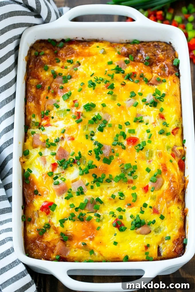 Delicious Hash Brown Egg Casserole Recipe with Ham and Cheese | Perfect Breakfast Casserole | Easy Ham and Egg Casserole | Cheesy Hash Brown Breakfast Bake A golden-brown hash brown egg casserole in a white baking dish, fresh from the oven, ready to be served.