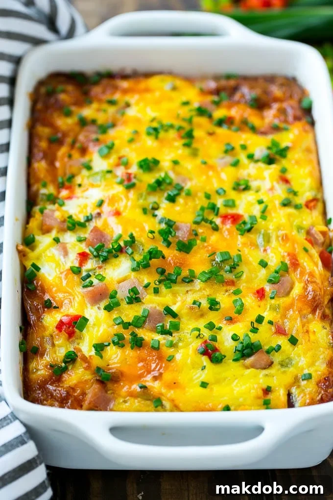 Hearty Hash Brown Casserole with Ham and Veggies | Cheesy Breakfast Bake for a Crowd A hearty hash brown casserole with ham, vegetables, and melted cheese, served in a large baking dish, ready to be portioned.