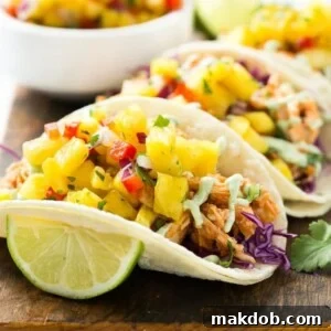 Delicious pulled chicken tacos topped with a sweet and tangy pineapple salsa and a creamy cilantro sauce, all served in warm corn tortillas.