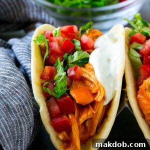 Bold buffalo chicken tacos featuring spicy shredded chicken, fresh diced tomatoes, crisp shredded lettuce, and a drizzle of creamy ranch dressing.