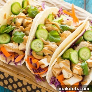 Delicious Thai chicken tacos, featuring coconut marinated chicken, fresh vegetables, and a generous dollop of homemade peanut sauce.