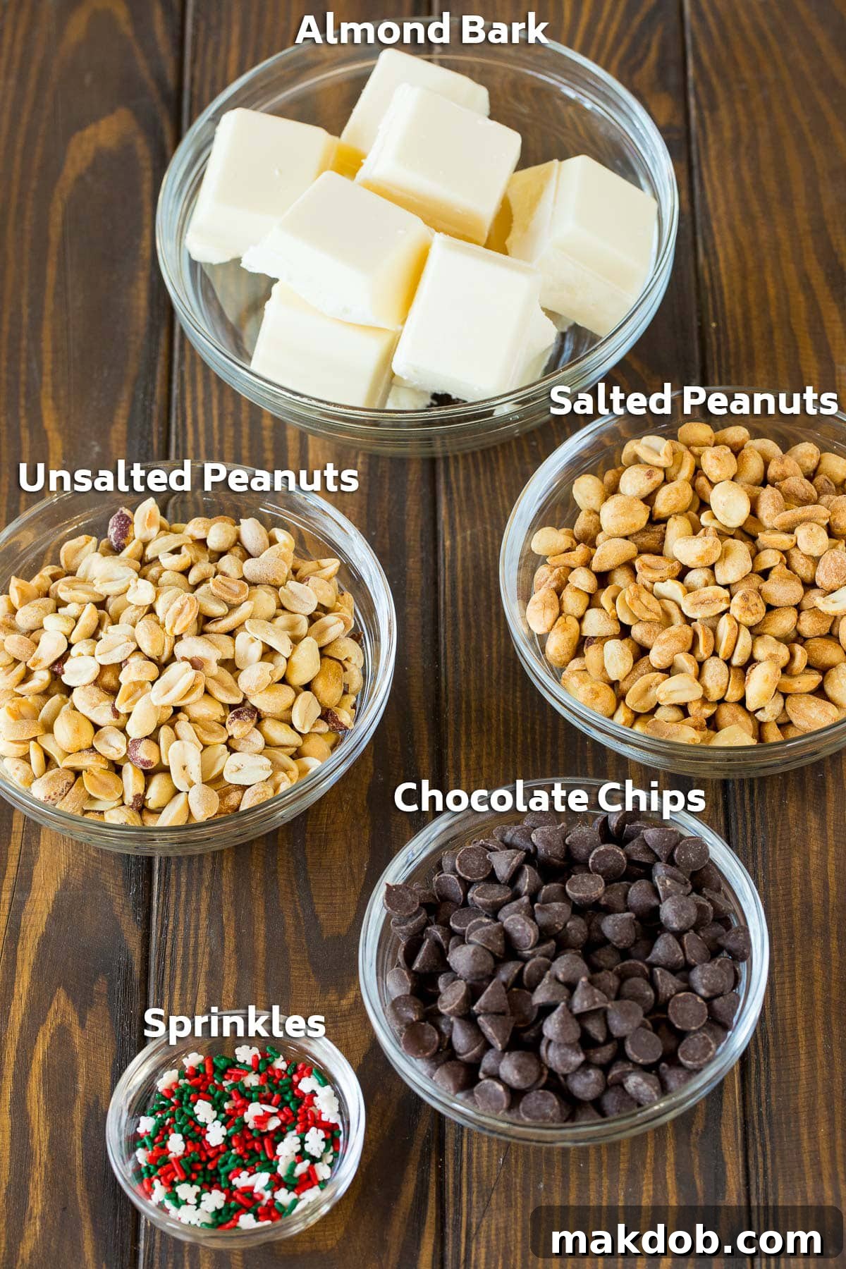 Bowls neatly arranged with the key ingredients for slow cooker peanut clusters: roasted peanuts, semisweet chocolate, almond bark, and colorful holiday sprinkles.