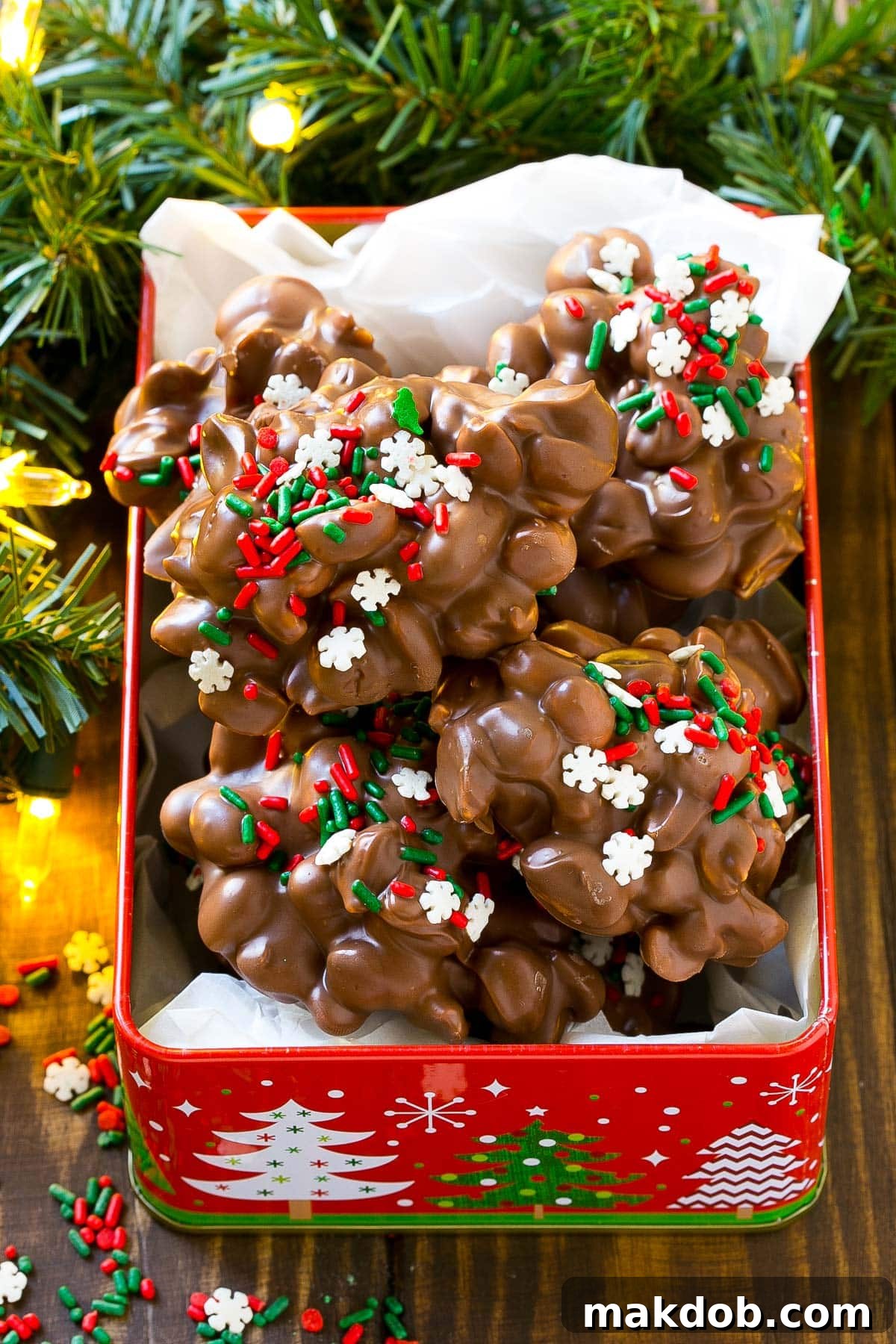 A festive close-up of crock pot candy peanut clusters neatly arranged in a charming decorative tin, ready to be presented as a thoughtful gift.