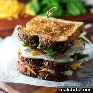 An image of two turkey club sandwiches on a cutting board.