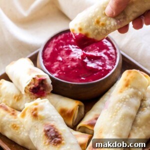 30 Creative Ways to Reinvent Leftover Turkey 23 A picture of turkey, cranberry and brie eggrolls on a plate with one being dipped in sauce.