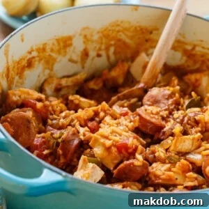 An image of a pot of chicken jambalaya with a wooden spoon in it.