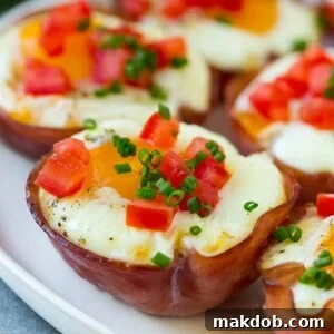 A plate of Ham and Egg Cups, elegantly topped with diced tomatoes and fresh chives, ready for a delightful breakfast.