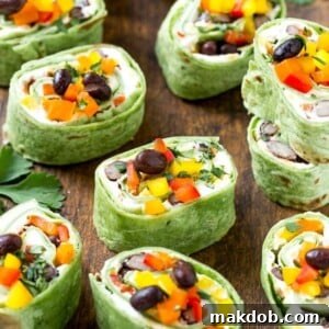 This recipe for Mexican tortilla pinwheels is two types of cheese, black beans and colorful veggies all rolled up inside tortillas and cut into rounds. The perfect make-ahead snack or appetizer!