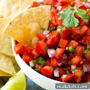 A bowl of pico de gallo with a tortilla chip in it.