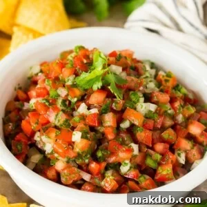 A bowl of salsa fresca served with chips.