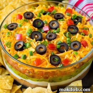 A bowl of 7 layer dip surrounded with tortilla chips.
