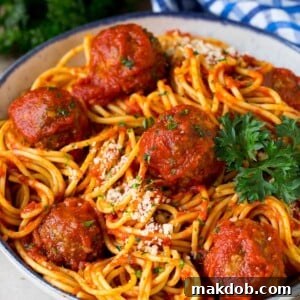 A generous serving bowl of crock pot spaghetti, adorned with homemade meatballs and a sprinkle of grated cheese, ready to be enjoyed.