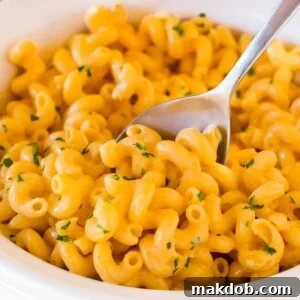 Slow cooker mac and cheese topped with parsley, with a serving spoon in it.