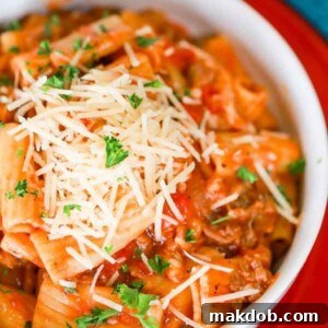 A mouth-watering picture of a slow cooker pasta featuring hearty Italian sausage and rigatoni, coated in a rich sauce.