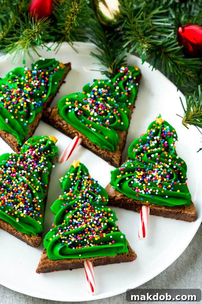 Delightful Christmas Brownies | Easy Holiday Treat | Festive Fudge Desserts #christmasdessert #holidaytreats #brownies Christmas Brownies beautifully decorated with green frosting and vibrant rainbow sprinkles, elegantly presented on a plate.