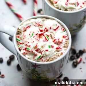 A warm mug of Homemade Peppermint Mocha coffee, topped with a generous swirl of whipped cream and a sprinkle of crushed candy canes, perfect for a cozy holiday treat.