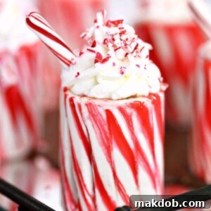 An adorable Candy Cane Cup, resembling an edible shot glass, topped with a swirl of whipped cream, inviting you to fill it with your favorite festive drink.