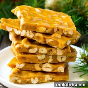 Crispy peanut brittle, expertly stacked onto a serving plate, highlighting its golden hue and nutty texture.