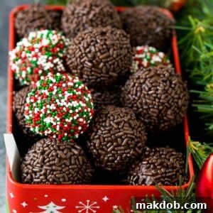 A festive tin filled with rum balls, charmingly coated in holiday sprinkles, perfect for a grown-up treat.