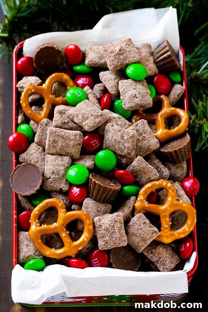 A tin of reindeer chow with chocolate coated chex, M&M's and pretzels.