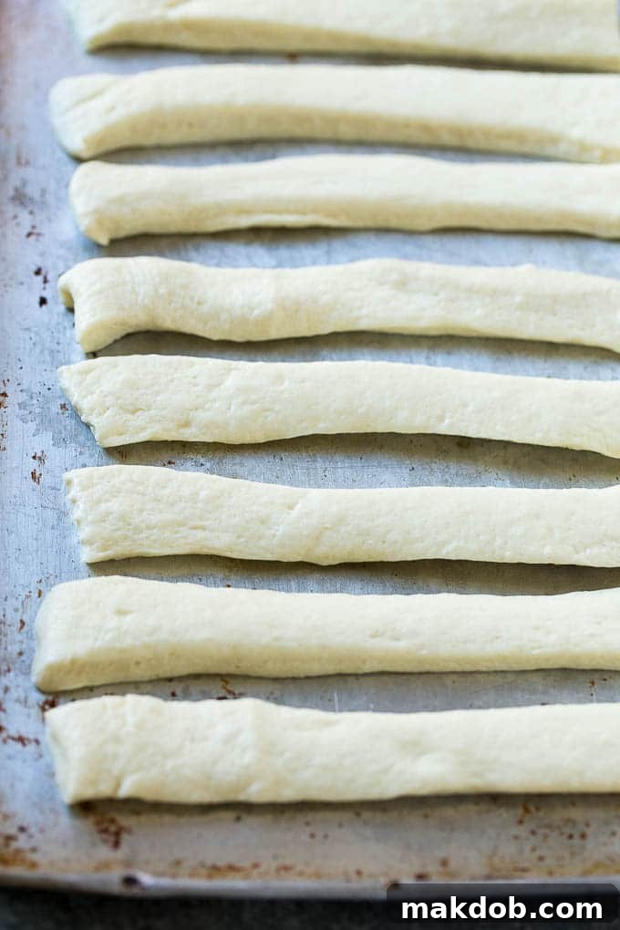 Pizza Dough Strips for Garlic Knots Strips of pizza dough on a sheet pan that are ready to be tied up.