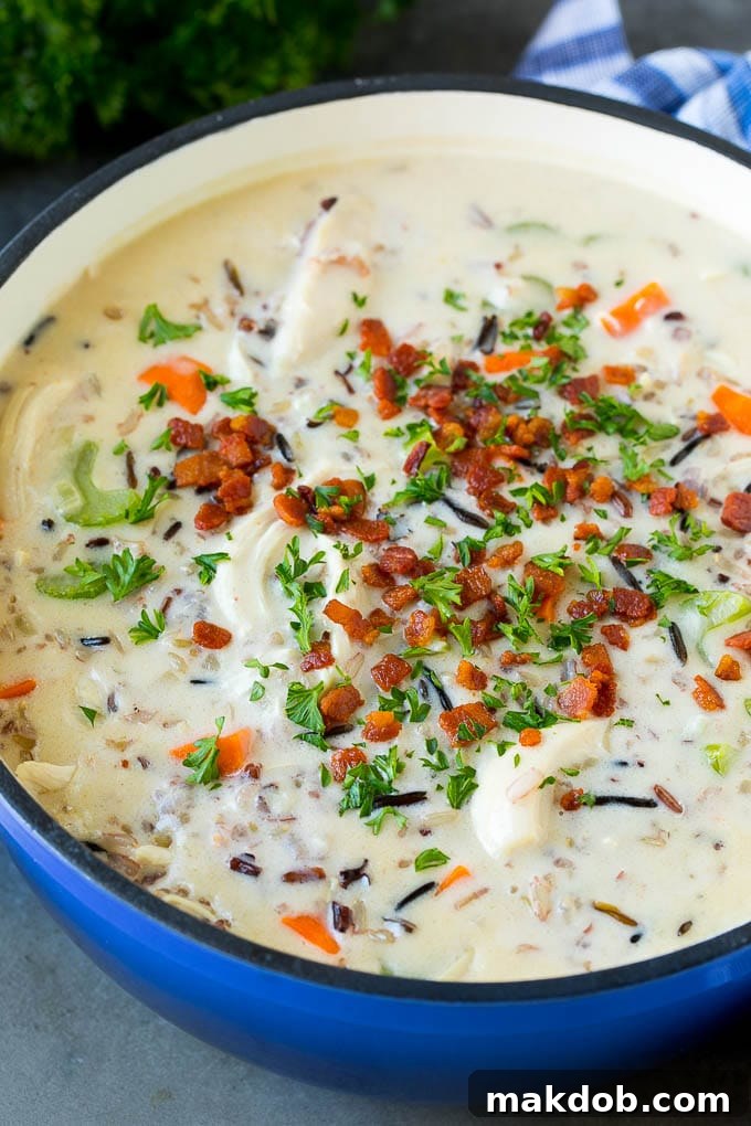 A pot of creamy chicken and wild rice soup with vegetables and bacon.