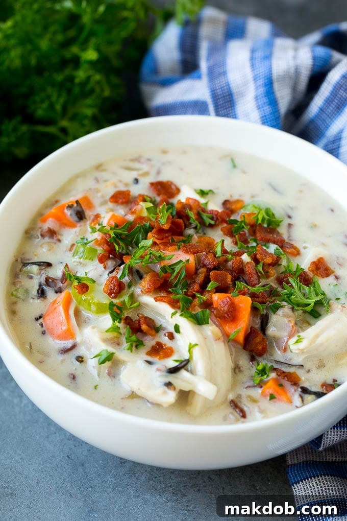 A bowl of chicken and wild rice soup topped with bacon and parsley.