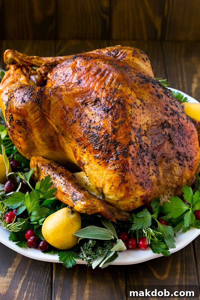 A whole herb roasted turkey surrounded by fresh herbs and colorful fruit, perfectly golden brown and ready to serve for a holiday feast.