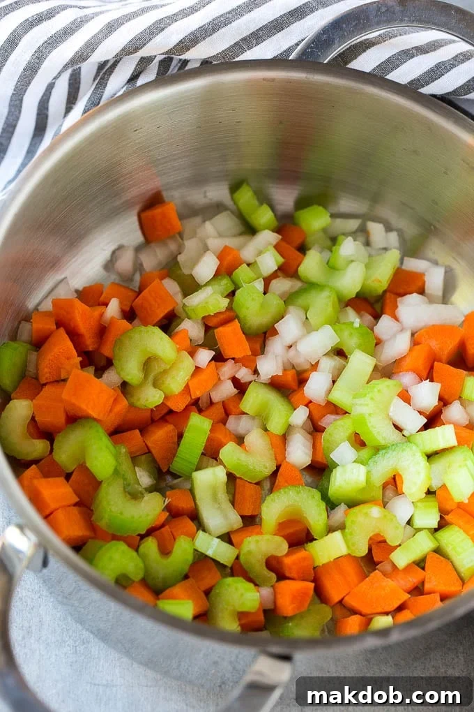 Loaded Burger Soup 3 A large pot on the stove with sautéed onions, carrots, and celery, forming the aromatic base of the soup.