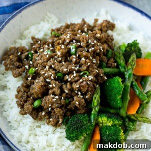 A bowl of fluffy rice topped with savory Korean ground beef and a colorful mix of vegetables.