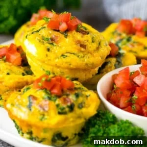 Breakfast egg muffins on a serving plate garnished with tomato and herbs, ready for a quick meal.