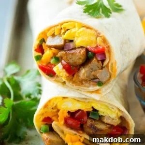 A cross section of a breakfast burrito generously filled with eggs, sausage, beans and cheese.