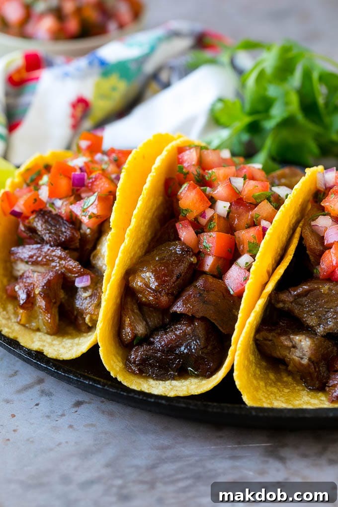 Pork carnitas tacos in corn tortillas, topped with pico de gallo.