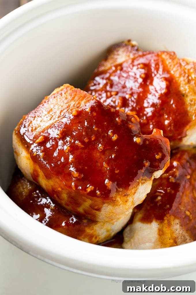 Browned pork chops in honey garlic sauce inside a crock pot.