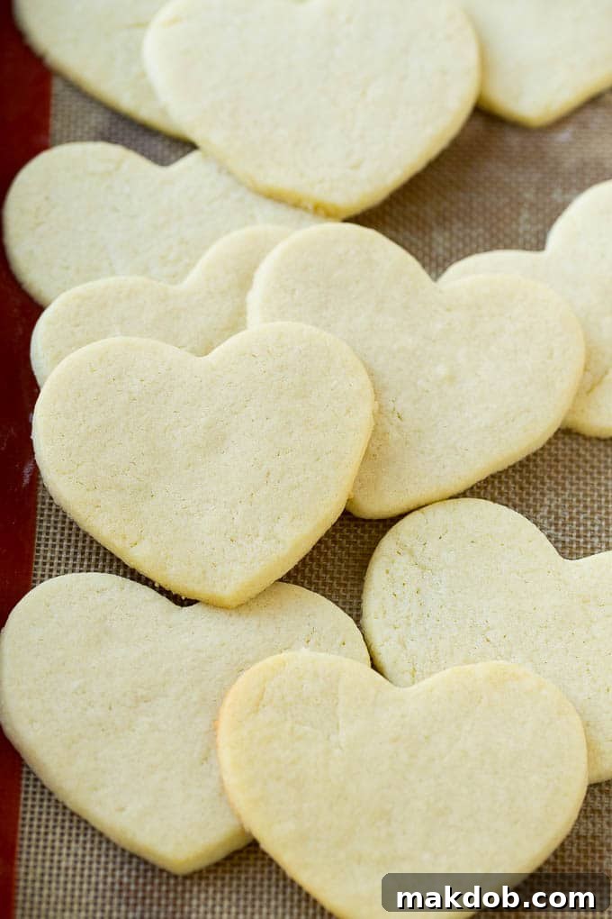 Freshly baked golden-brown heart shaped sugar cookies cooling on a wire rack.