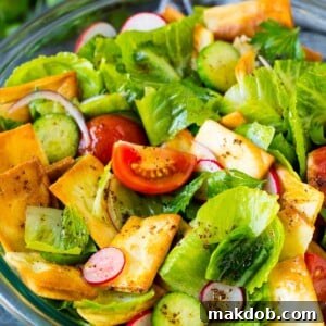 A bowl of fattoush salad with tomatoes, radishes and pita chips.