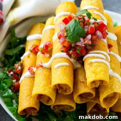 A stack of chicken taquitos with a drizzle of sour cream and pico de gallo topping.